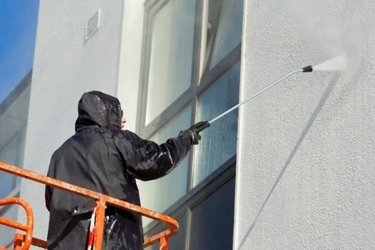 un façadier effectuant un traitement de façade sur une immeuble